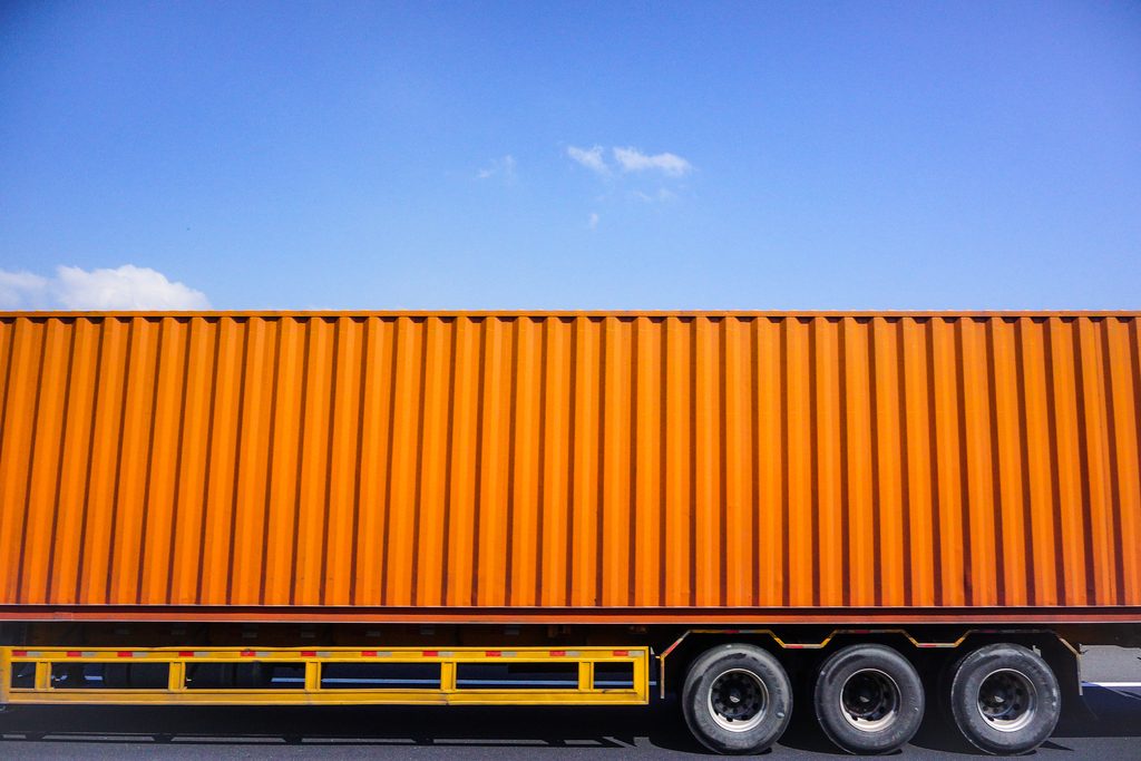 Orange container on a trailer under blue sky